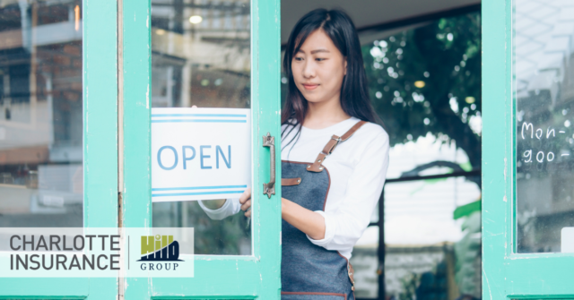 a small business owner hanging an 'open' sign on their door